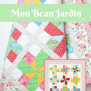 Op de afbeelding: Een quiltpatroon genaamd "Mon Beau Jardin" #140, ontworpen door Nadra Ridgeway. Het patroon heeft een kleurrijk patchwork-ontwerp met een bloemenprint en een kleiner voorbeeld van het patroon in de rechterbenedenhoek. De quilt is 63 1/2 inch bij 63 1/2 inch.