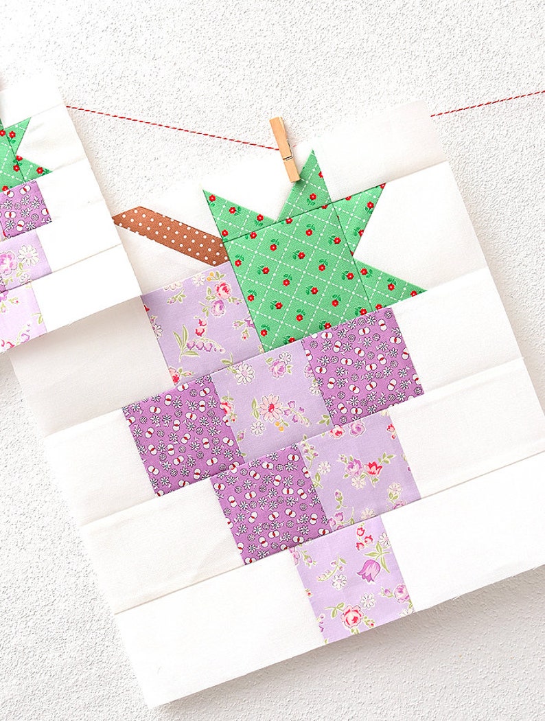 May include: A quilt block featuring a green star in the centre and a purple and white floral design in the background.