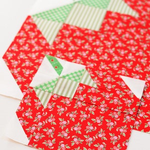 Peut inclure: Un bloc de courtepointe patchwork rouge et vert avec un motif g&eacute;om&eacute;trique. Le bloc est compos&eacute; de carr&eacute;s et de triangles de tissus diff&eacute;rents.