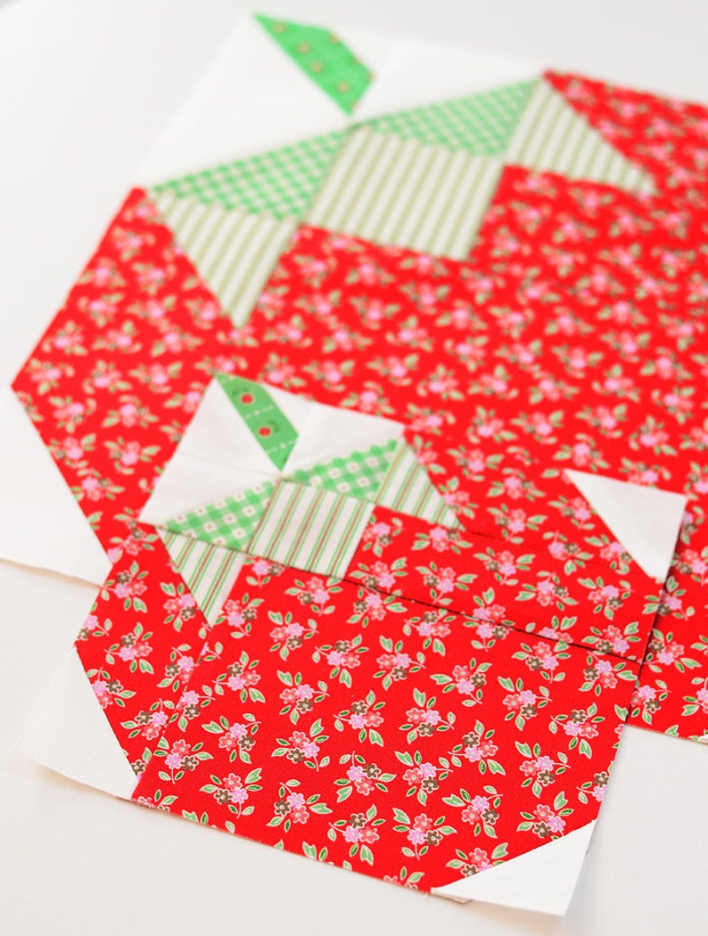 Peut inclure: Un bloc de courtepointe patchwork rouge et vert avec un motif g&eacute;om&eacute;trique. Le bloc est compos&eacute; de carr&eacute;s et de triangles de tissus diff&eacute;rents.