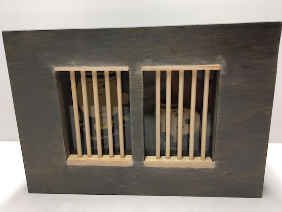 This is a wooden coin bank that shows Charlie Brown and Snoopy in jail.