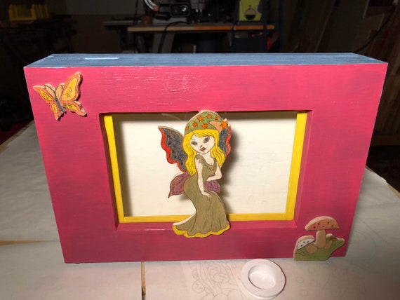 Wooden coin bank with a fairy, a butterfly, and a mushroom.