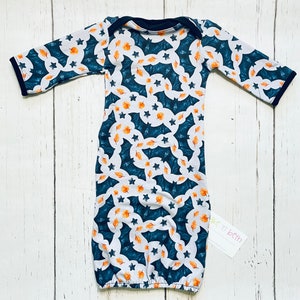 Puede incluir: Un camis&oacute;n de beb&eacute; con un estampado azul marino, blanco y naranja. El estampado presenta murci&eacute;lagos, estrellas y hojas. El camis&oacute;n tiene mangas largas con ribete azul marino y un escote azul marino. El camis&oacute;n est&aacute; hecho de tela suave.