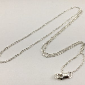 May include: A silver chain necklace with a lobster clasp closure.