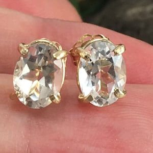 May include: A pair of gold oval-shaped earrings with clear gemstones.