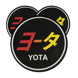 May include: Three black and white round patches with a white border. The center patch has the Japanese word "YOTA" in white letters and the Japanese characters for "YOTA" in red and yellow. The other two patches have the Japanese characters for "YOTA" in black.