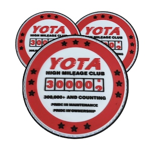 May include: Three red and white round rubber patches with the text "YOTA HIGH MILEAGE CLUB" and a digital display reading "300,000+ AND COUNTING".