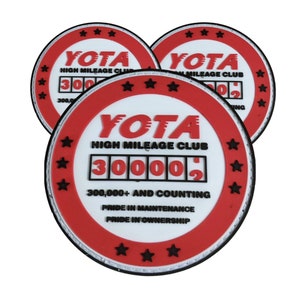 May include: Three red and white round rubber patches with the text "YOTA HIGH MILEAGE CLUB" and a digital display reading "300,000+ AND COUNTING".