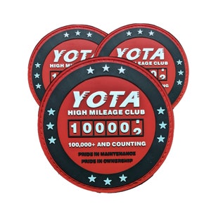 May include: Three red and black round patches with white text. The center patch reads "YOTA HIGH MILEAGE CLUB 10000 100,000+ AND COUNTING PRIDE IN MAINTENANCE PRIDE IN OWNERSHIP".