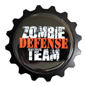 May include: Black metal gear-shaped pin with the text "Zombie Defense Team" in white and orange lettering.