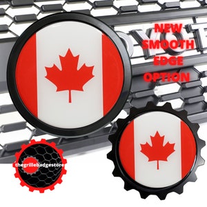 May include: Two black and red Canadian flag car emblems. The larger emblem has a smooth edge and the smaller emblem has a gear-shaped edge. The text "NEW SMOOTH EDGE OPTION" is visible in the background.