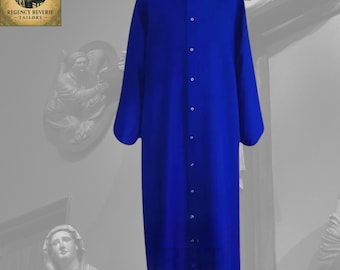 May include: A long, royal blue robe with a mandarin collar and white trim. The robe has long sleeves and a button-down front. The garment is displayed against a neutral background. The logo for Regency Reverie Tailors is in the upper left corner.