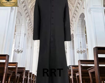 May include: A long, black clerical robe with a white collar and button-down front. The robe is floor-length and has long sleeves. The letters "RRT" are visible on the lower part of the robe. The background is a church interior.
