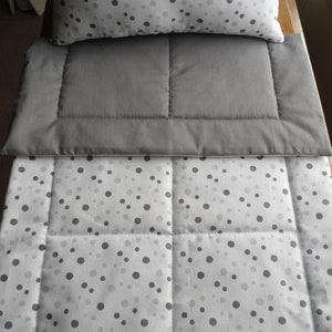 May include: A gray and white patterned comforter with a gray quilted top layer. The comforter has a white background with small gray polka dots.