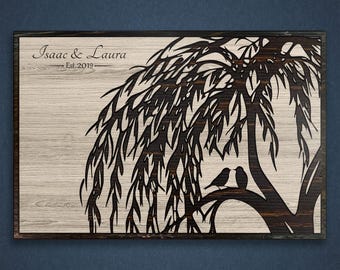 May include: A wooden sign with a black silhouette of a weeping willow tree and two birds perched on a branch. The text "Isaac & Laura Est. 2019" is engraved on the top of the sign.