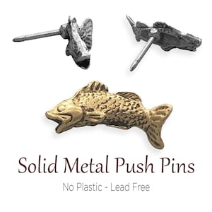 May include: Three solid metal push pins in the shape of fish. One is gold-colored, and two are silver-colored. The text "Solid Metal Push Pins" and "No Plastic - Lead Free" are below the pins.