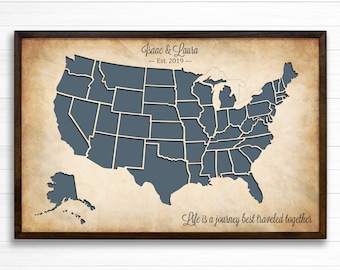 May include: A framed map of the United States with each state outlined in gray. The map is on a vintage-style background with the text "Isaac & Laura - Est. 2019 - Life is a journey best traveled together".