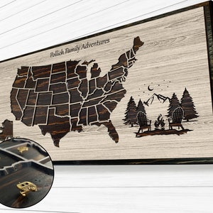 May include: A wooden map of the United States with a cutout of each state. The map is light brown with dark brown state outlines. The text "Pollich Family Adventures" is at the top of the map. There is a small campfire scene with two chairs and a crescent moon in the upper right corner of the map.