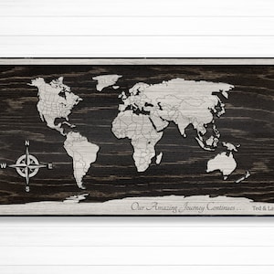 May include: A wooden world map with a compass and the text "Our Amazing Journey Continues... Ted & Laurie".