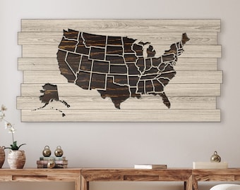 May include: A wooden wall art piece featuring a cutout map of the United States with each state outlined. The map is dark brown and the wood background is light brown.