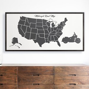 May include: A black and white map of the United States with state borders outlined. The map is framed in black and has the text "Motorcycle Road Map" at the top. A black silhouette of a motorcycle is on the right side of the map.