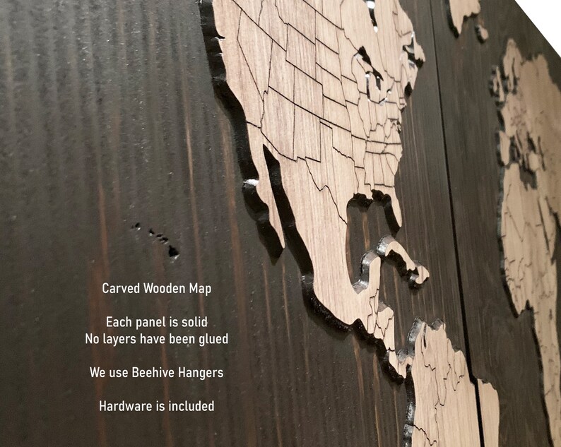 K&ouml;nnte beinhalten: Eine geschnitzte Weltkarte aus Holz mit einer dunkelbraunen Beize. Die Karte besteht aus zwei Teilen, einer zeigt Nord- und S&uuml;damerika und der andere Europa, Afrika, Asien und Australien. Der Text "Carved Wooden Map" ist am unteren Rand des Bildes sichtbar. Der Text "Each panel is solid" ist unter der Karte sichtbar. Der Text "No layers have been glued" ist unter dem vorherigen Text sichtbar. Der Text "We use Beehive Hangers" ist unter dem vorherigen Text sichtbar. Der Text "Hardware is included" ist unter dem vorherigen Text sichtbar.