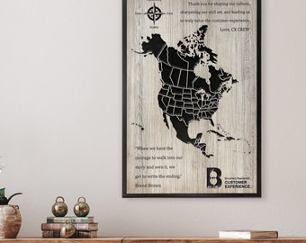 May include: A framed wooden wall art piece featuring a black map of North America. The artwork includes text with a compass rose, a quote by Brené Brown, and the words "Customer Experience."