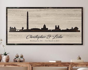 May include: A wood sign with a black silhouette of the Washington, D.C. skyline. The text "Christopher & Leslie" is written below the skyline, along with "Washington, D.C. | Est March 2, 2013".