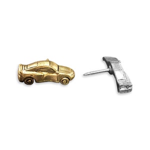 May include: A gold-colored car pin and a silver-colored pin shaped like a car with a pin on the back.