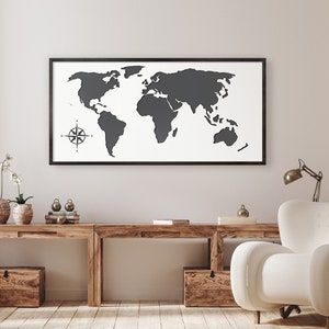May include: A black framed world map print with a compass design in the bottom left corner hangs above a wooden desk with two chairs. The desk has a drawer on the left side and a shelf on the right side.