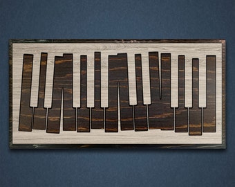 May include: A wooden sign with a black outline of a piano keyboard. The sign is made of light wood with dark wood grain.