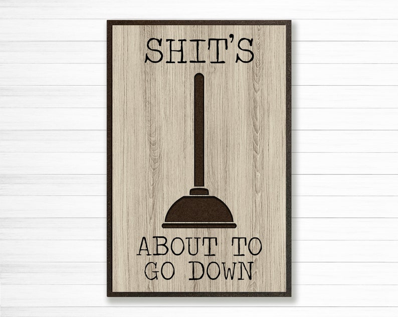 May include: A brown wooden sign with a black outline and the text "SHIT'S ABOUT TO GO DOWN" with a black silhouette of a plunger in the middle.