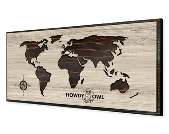 May include: A wooden world map with a distressed wood finish. The map is cut out and the continents are raised. The map is framed in a dark wood frame. The text "HOWDY OWL" is printed below the map.