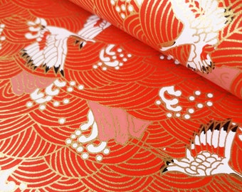 May include: Red and gold patterned wrapping paper with a white crane design. The pattern features a repeating wave design.