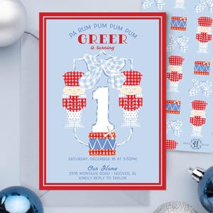 May include: A blue and red invitation card with a red border. The card features a cartoon illustration of two drummers with a large number 1 in the center. The text on the card reads "Pa Rum Pum Pum Pum Greer is turning 1" and includes details for a party on December 16th at 5:30pm.