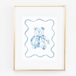 May include: A framed watercolor illustration of a blue patchwork teddy bear with a blue bow. The bear is sitting in a blue wavy frame.