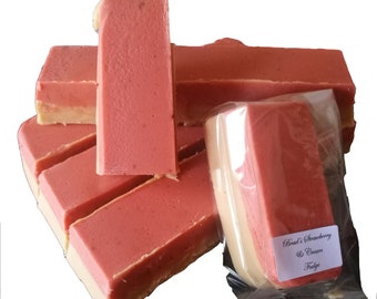 May include: A stack of pink and white strawberry and cream fudge bars. The bars are wrapped in clear plastic and labeled "Brad's Strawberry & Cream Fudge".
