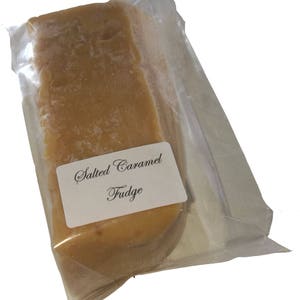 May include: A pack of salted caramel fudge. The fudge is a light brown colour and is wrapped in clear plastic. The pack has a white label that says "Salted Caramel Fudge".