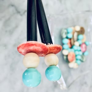May include: A pair of earrings with black wooden posts, red and white shell-like tops, and three beads each: white, turquoise, and turquoise.