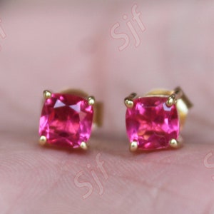 May include: A pair of gold stud earrings with square pink gemstones.