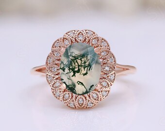 May include: A rose gold ring with a green and white moss agate oval gemstone surrounded by a halo of small diamonds.