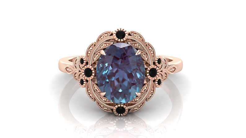 Puede incluir: Anillo de oro rosa con una piedra preciosa de alejandrita ovalada que cambia de color. El anillo presenta un dise&ntilde;o floral detallado con detalles en negro. La banda tiene un patr&oacute;n de filigrana ornamentado.