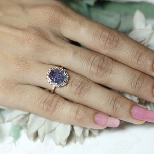 May include: A rose gold ring with a large oval-shaped purple gemstone surrounded by smaller white gemstones.