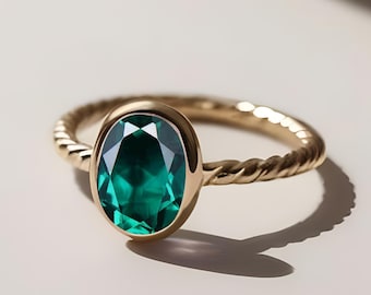 May include: A gold ring with a twisted band and a large, oval-shaped emerald green gemstone.