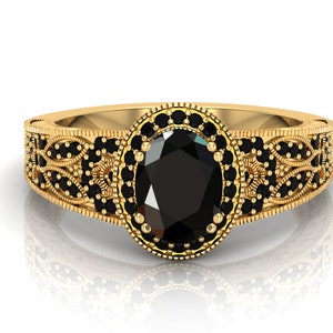 May include: A gold ring featuring an oval black gemstone encircled by smaller black gemstones. The ring boasts a delicate, intricate design.