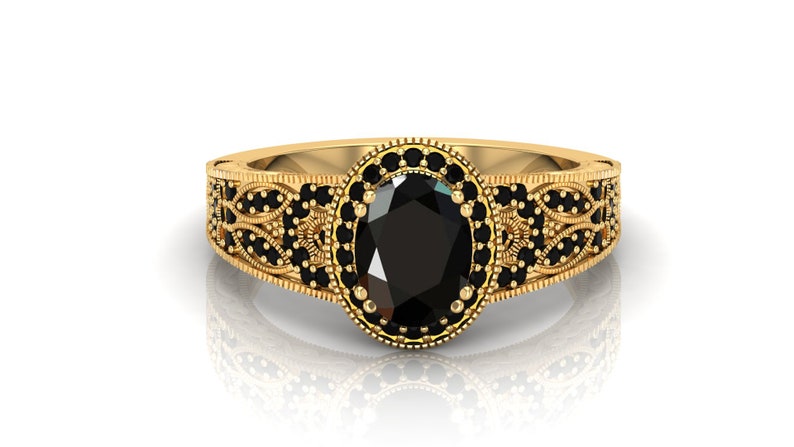 May include: A gold ring featuring an oval black gemstone encircled by smaller black gemstones. The ring boasts a delicate, intricate design.