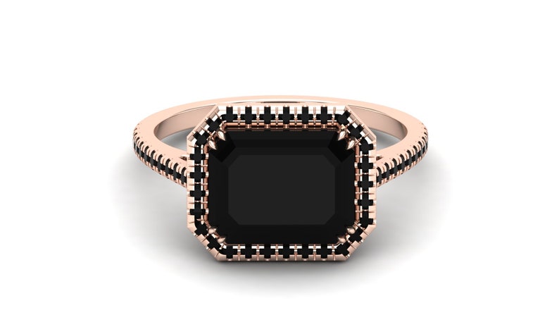 Op de afbeelding: Ros&eacute;gouden ring met een grote, rechthoekige zwarte edelsteen. De edelsteen is omgeven door een halo van kleinere zwarte stenen, met extra zwarte stenen langs de band. De ring heeft een klassiek, elegant ontwerp.