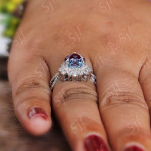 May include: A silver ring with a large, round, blue and red gemstone surrounded by smaller, clear gemstones.