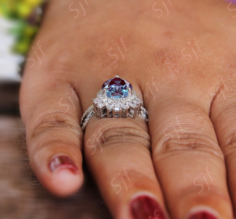 May include: A silver ring with a large, round, blue and red gemstone surrounded by smaller, clear gemstones.
