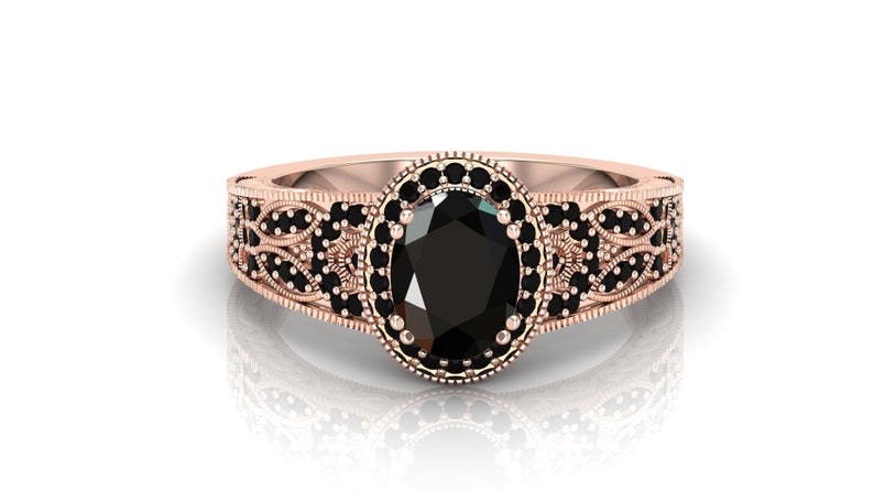 May include: A rose gold ring featuring an oval black gemstone set within a halo of smaller black gemstones. The band is adorned with a filigree design.